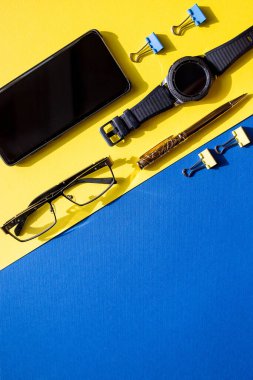 Serbest blog yazarı için düz kompozisyon. Çalışma alanı kalem, şık akıllı telefon, renkli arka planda siyah saat. İş konsepti. Modern yaşam tarzı.