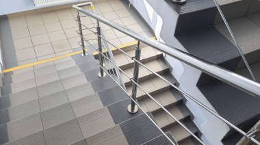 Çok katlı bir binanın girişindeki merdiven. Merdivenlerde basamaklar var. İnişten aşağıya bak.