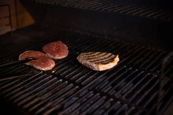 Pyszne grillowane mięso z warzywami na węglu na grillu.Przygotowanie hamburgerów na grillu. Smaczne steki wołowe na grillu. soczysty i apetyczny stek. Skupienie selektywne. — Zdjęcie stockowe