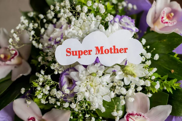 Las palabras Super Mamá escritas en un papel blanco mierda aislado fondo floral. Concepto de amor por las madres.Ramo de flores .Postcard con flores frescas y carta para usted . —  Fotos de Stock