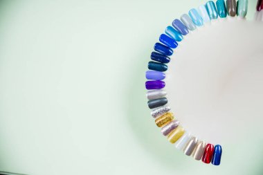 Tırnak cilası örnekleri farklı renklerde. Renkli manikür bezi örnekleri. Tırnak sanatı çarkı paletinin üst görüntüsü. Profesyonel manikürler için oje paleti.