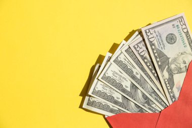 Bir yığın Amerikan doları, açık kırmızı bir zarfın içinde banknotlar, sarıya karşı izole edilmiş. Çevrimiçi alışveriş. Zenginlik ve refah. Zarfta nakit para var. İkramiye, ödül, ikramiye. Anlaşıldı.