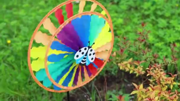 Kolorowe dekoracyjne wiatrak wyglądają pięknie wokół wieje wiatr w ogrodzie.mała dziewczynka bawiąca się z pinwheel.multiccolored pinwheel poruszane przez wiatr. — Wideo stockowe