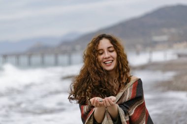 Çizgili panço çakıl onun avuç içi tutan genç kadın