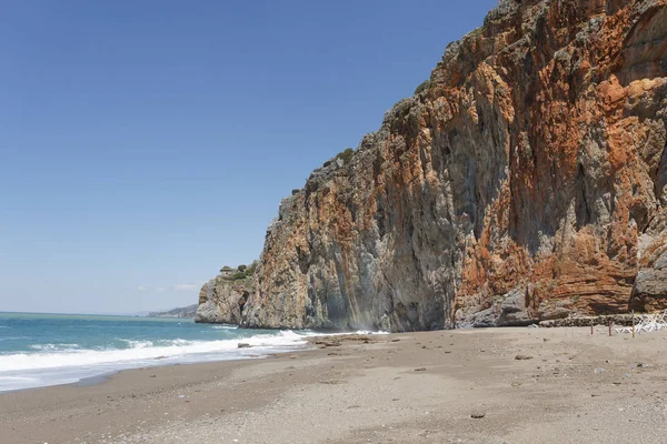 Όμορφη παραλία με άμμο και βότσαλα, πίσω από τον κόκκινο βράχο — Φωτογραφία Αρχείου