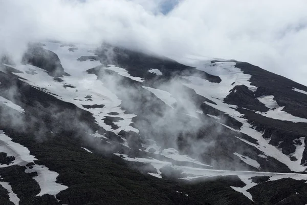 Pentes montagneuses couvertes de neige fondante et de nuages — Photo