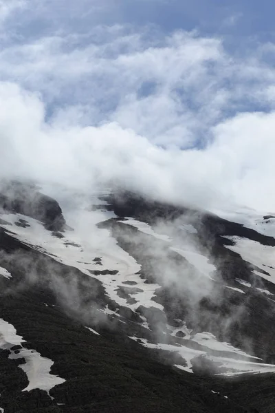 Pente montagneuse couverte de neige fondante et de nuages — Photo