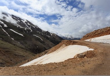 Eriyen kar ve bulutlar ile kar zirveleri ile dağ manzarası