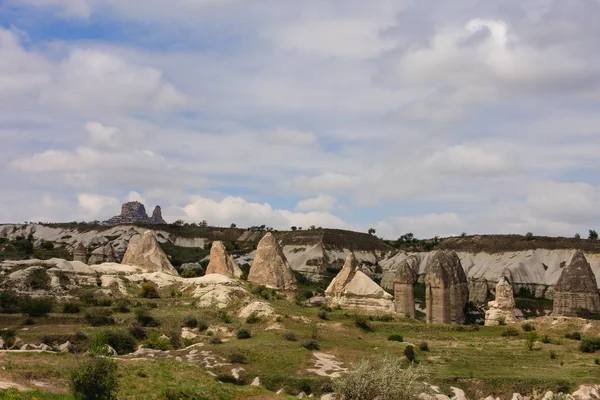 Horizontal shot of fairy chimneys of Cappadocia in Turkey in spring with green grass and small trees shot on cloudy days — Stock Photo, Image