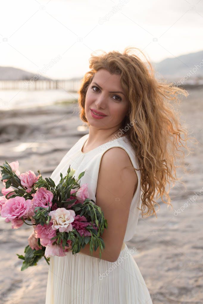Beautiful woman in white dress holding bouqet of pink lisianthus