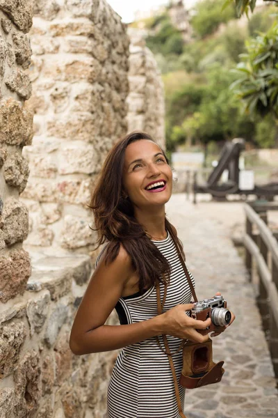 Travelling woman holding vintage camera in her hands and smiling — Stock Photo, Image