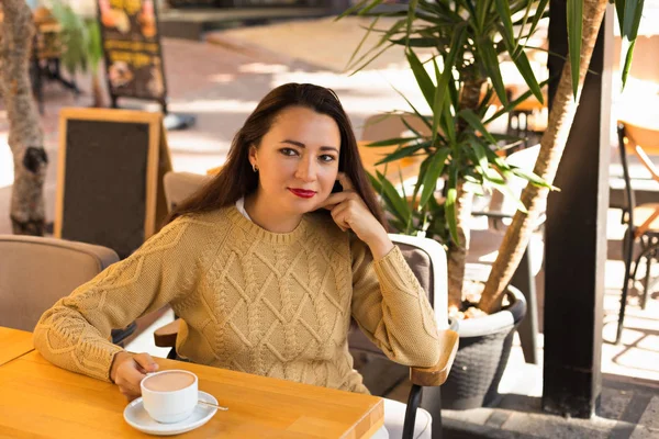 Feminino em camisola quente no café ao ar livre bebendo chocolate quente — Fotografia de Stock