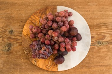 Kırmızı üzüm ve Erik mermer ve ahşap arka plan