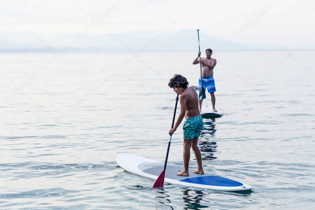 Boy and farther practicing stand up paddles
