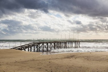 Sandy kış plajı ile deniz ve kasvetli gökyüzü fırtınası iskele,