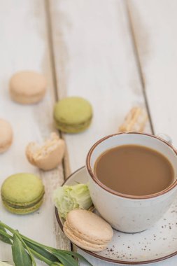 bir fincan kahve ile süt ve pembe ve yeşil macaroons
