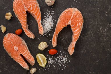 Kiraz domates, limon, sarımsak ve solt blakk masa üzerinde üç somon kazık. Topview. Copyspace.