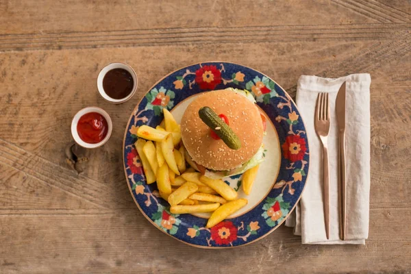 Гамбургер с картошкой фри в тарелке с орнаментами — стоковое фото