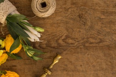 Beyaz mumlar, lisianthus, sarı ranunculus ve kopya alanı ile ahşap rustik masa üzerinde vintage mumluk ile Flatlay.