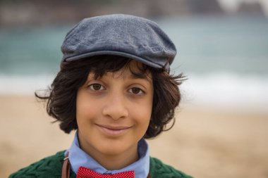 Baş ve omuzlar düz kapak ve kırmızı papyon giyiyor uzun saçlı esmer bir çocuk portresi