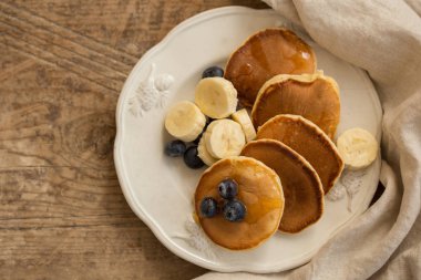 Yaban mersini ve muz ile rustik ahşap masa üzerinde beyaz seramik plaka krep Üst görünüm çekim.