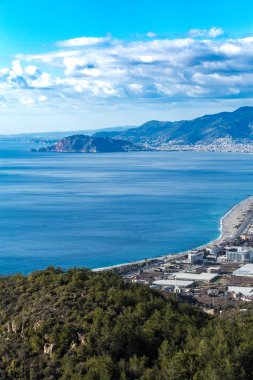 Kuş bakışı, Akdeniz'in kıyı kenti Alanya'nın Türkiye'de ön planda çam ormanı ile kaplı tepe ve alanya'nın kale kayası ile uzak görüşte. Dikey kompozisyon.