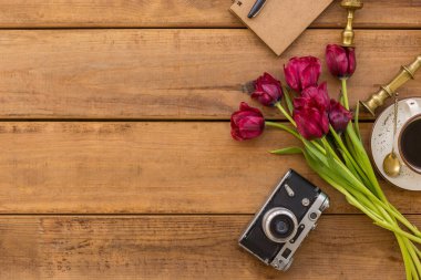 Bahar düz mor lale, vintage kamera, kahve fincan ve ahşap masa üzerinde vintage mumluklar ile yatıyordu. Negatif boşluk. Yatay kompozisyon.