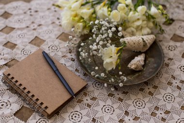 Rustik düğün planlama konsepti. Siyah kalem ve küçük fresia ve gypsophila çiçek bouqet dantel masa üzerinde vintage plaka ile Not Defteri.