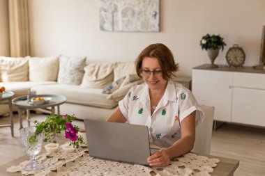 Serbest ve ev ofis konsepti. Gülümseyen orta yaş kadın ev ofisinden çalışan.