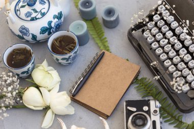Bahar ya da yaz yazma ve serbest kavramı. Retro daktilo, Not defteri, vintage film kamerası, bitkisel çay ve gül ile tarz workdesk.