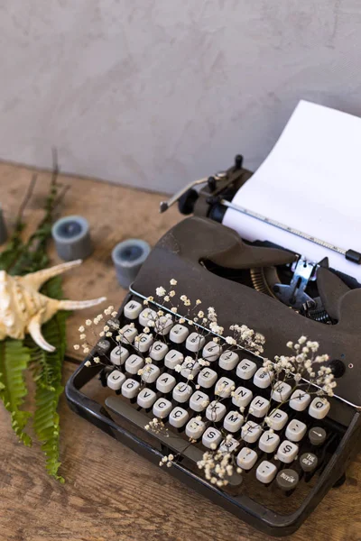 Spring or summer writing and freelance concept. Vintage typewriter with flowers between its keys. Copy space. Vertical composition.