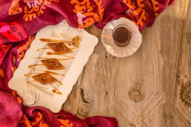 Üst görünümü ceviz ve çay rustik ahşap masa üzerinde beyaz seramik plaka ile geleneksel Azeri Baklava bir kadeh. Yatay kompozisyon. Kopya alanı.