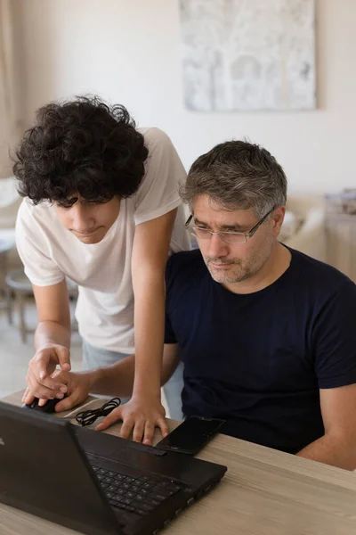 Papa et fils étudient de la maison ensemble en utilisant un ordinateur portable noir — Photo