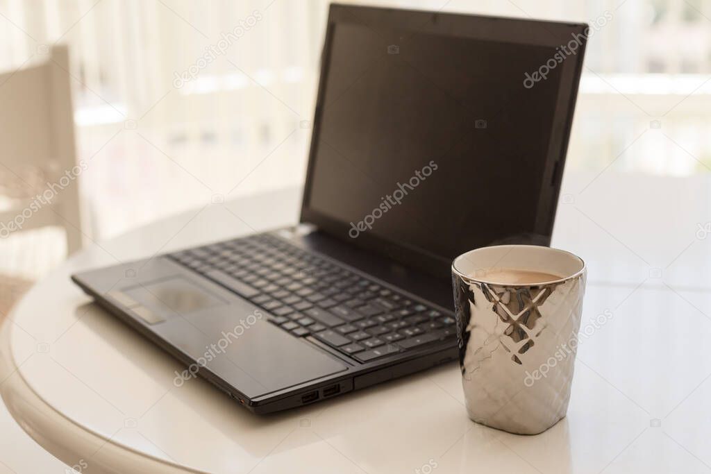 Home office mockup. A table with a cup of coffee and black laptop.