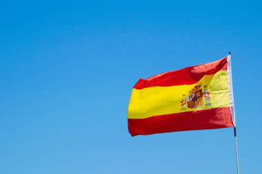 Rüzgarda dalgalanan bir İspanyol bayrağı ve arkasında mavi gökyüzü.