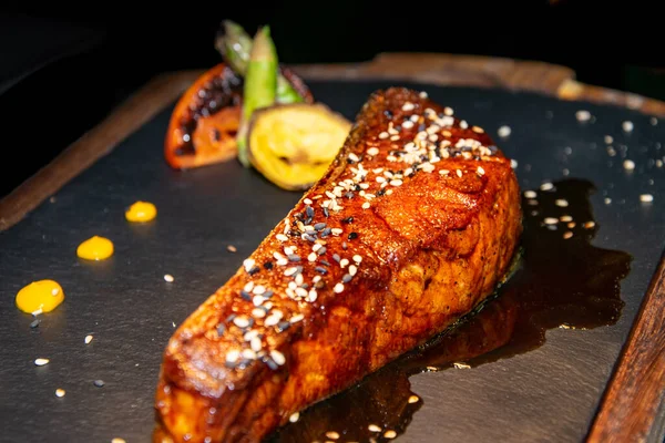 Teriyaki sosunda pişirilmiş bir parça Kanada somonu. Taş ve ahşap tabakta servis ediliyor. 