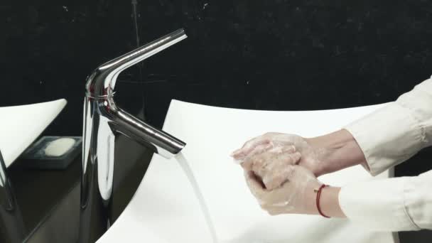 Kadın ellerini yıkıyor. Beyaz lavabo, siyah banyo. — Stok video