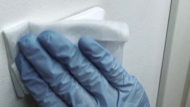 Limpieza del interruptor blanco en guantes con un paño blanco, coronavirus pandémico — Vídeo de stock