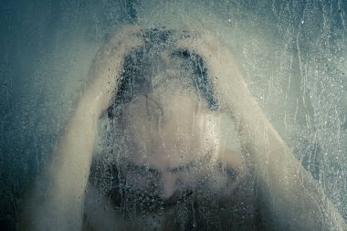 su akan ve duşakabin banyo şeffaf buğulu cam kapının arkasında kafasını tutarak altında ayakta duş alırken adam vurguladı