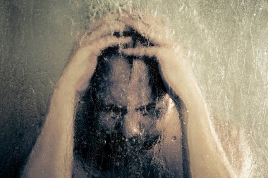su akan ve duşakabin banyo şeffaf buğulu cam kapının arkasında kafasını tutarak altında ayakta duş alırken adam vurguladı
