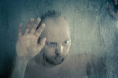 su akan ve duşakabin banyo şeffaf buğulu cam kapının arkasında kafasını tutarak altında ayakta duş alırken adam vurguladı