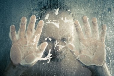 su akan ve duşakabin banyo şeffaf buğulu cam kapının arkasında kafasını tutarak altında ayakta duş alırken adam vurguladı