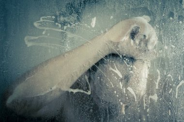 su akan ve duşakabin banyo şeffaf buğulu cam kapının arkasında kafasını tutarak altında ayakta duş alırken adam vurguladı