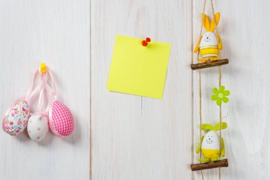 Yumurta dekorasyon Paskalya tavşanı beyaz tahta arka plan ile sarı etiket üzerinde.