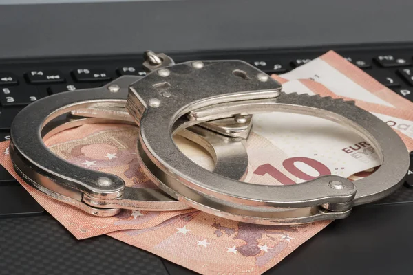 Laptop klavye üzerinde kelepçe altında para. Cyber hacker suç kavramı.
