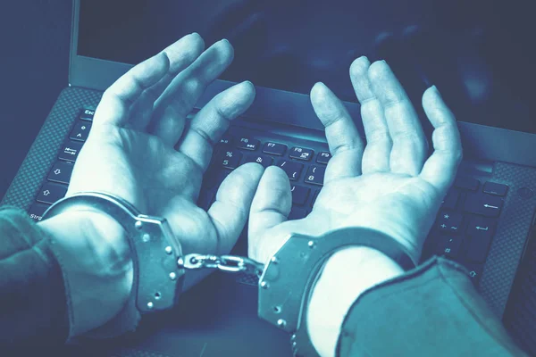 Laptop klavye üzerinde kelepçeli elleriyle tutuklandı hacker mavi mat tonlama resim. Siber suç kavramı. Eller üzerinde odaklanmak.
