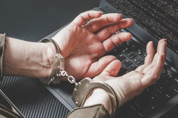 Hacker com as mãos atrás em algemas no teclado do laptop e código digital ao redor. Conceito de cibercriminalidade . — Fotografia de Stock