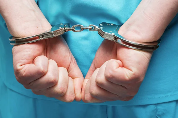 Doctor in blue uniform with stethoscope attached to handcuffed at the wrist. — Stock Photo, Image