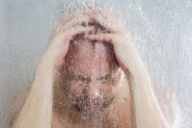 su akan ve duşakabin banyo şeffaf buğulu cam kapının arkasında kafasını tutarak altında ayakta duş alırken adam vurguladı