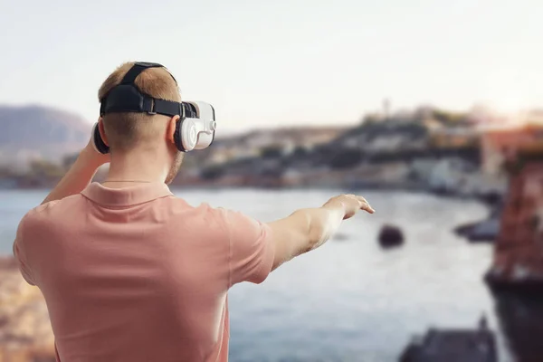 Young man using virtual reality glasses to tour in the sea landscape, on vacation in the summer. VR concept.